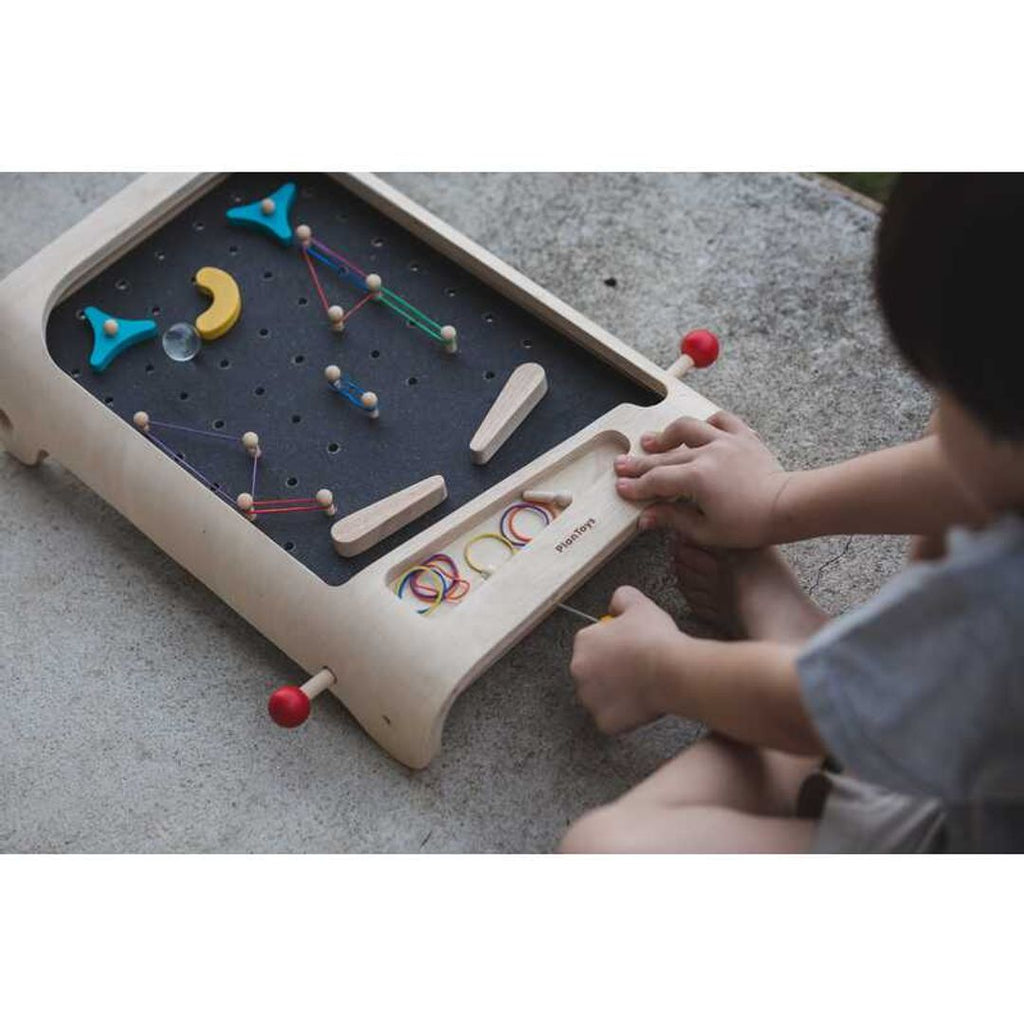 Kid playing PlanToys Pinball