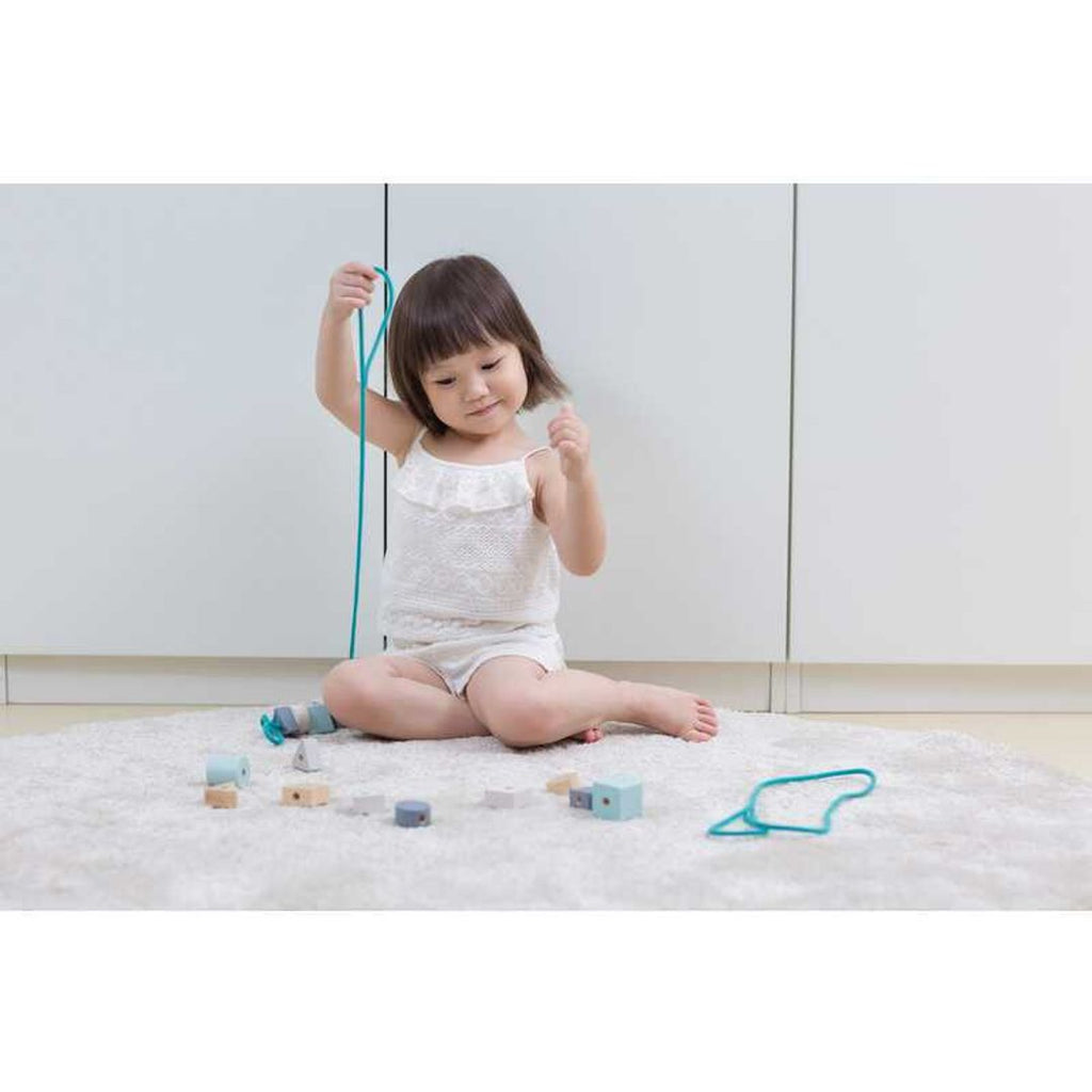 Kid playing PlanToys Geo Beads Lacing