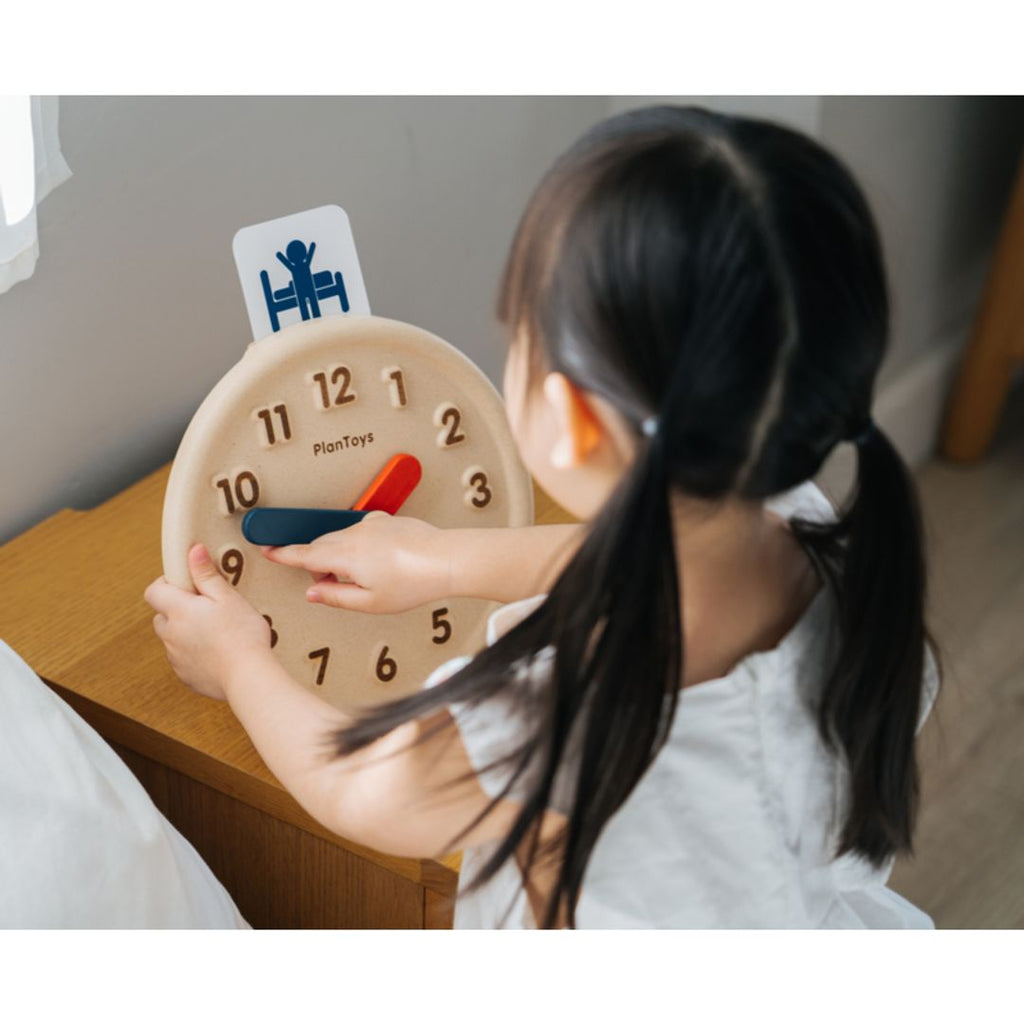 Kid playing PlanToys Activity Clock