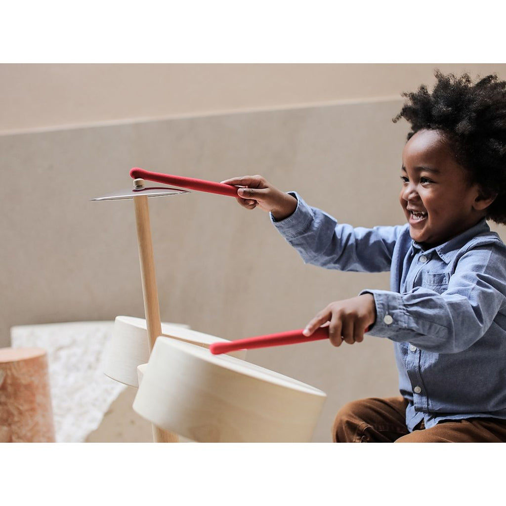 Kid playing PlanToys Drum Set