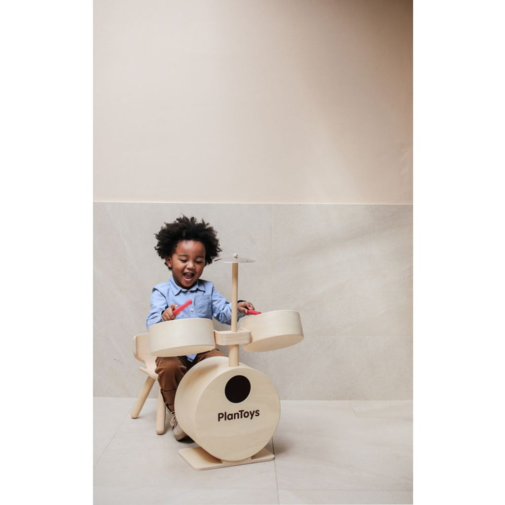 Kid playing PlanToys Drum Set