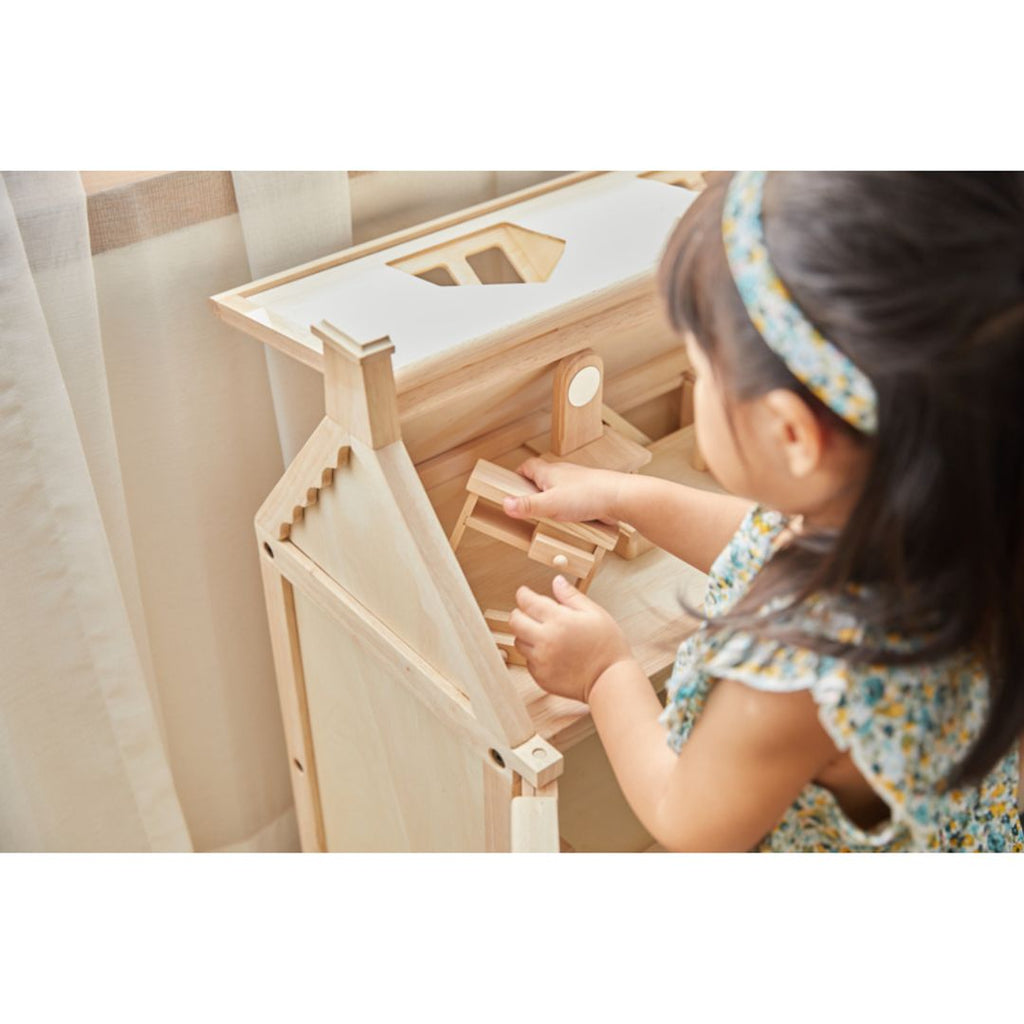 Kid playing PlanToys Victorian Dollhouse