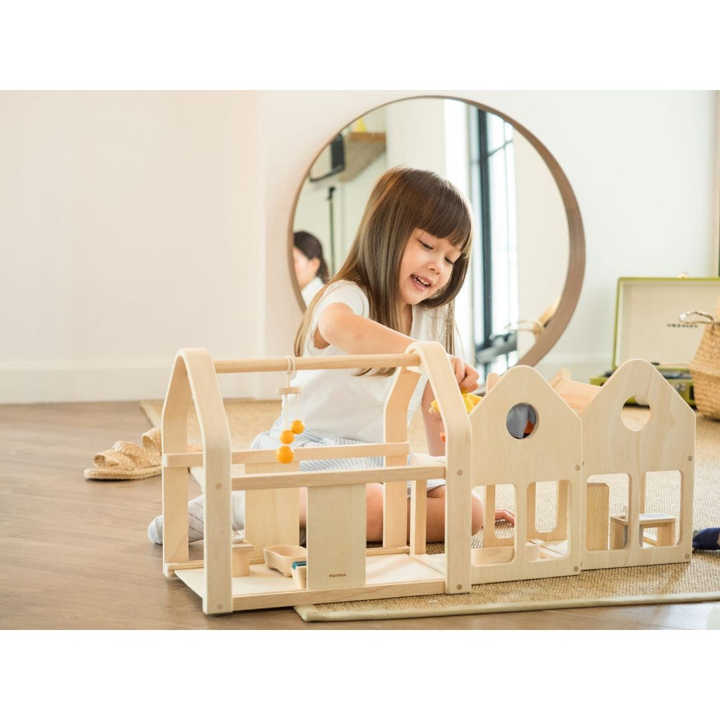 Kid playing PlanToys Slide N Go Dollhouse